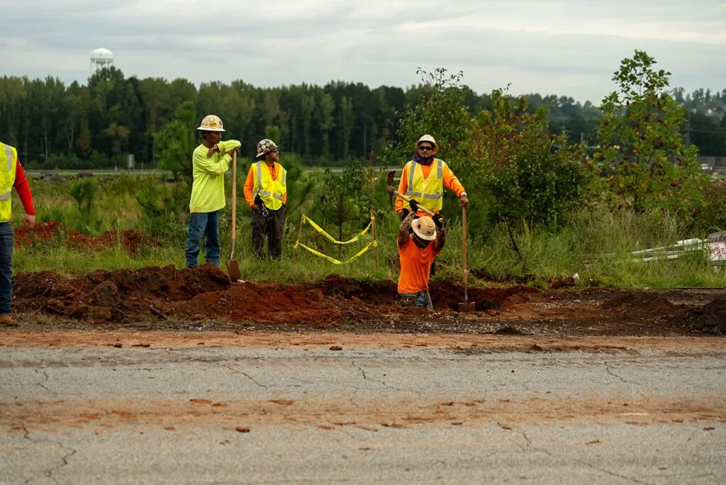 four major league milling employees working on the side of the road